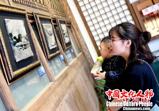 由泉州锡雕工艺师林慧创作的锡雕艺术作品《印象泉州》吸引一对母子观看。 记者刘可耕 摄 由泉州锡雕工艺师林慧创作的锡雕艺术作品《印象泉州》吸引一对母子观看。 记者刘可耕 摄
