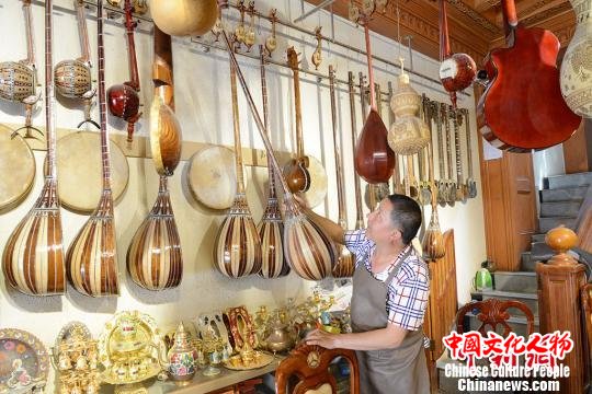 胡达白尔地将制作完成的一件都塔尔挂在墙上。　勉征 摄