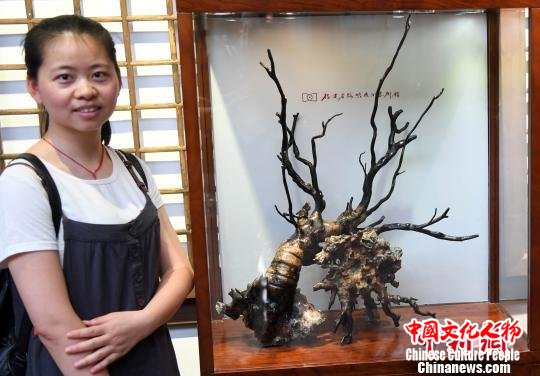 一名年轻女观众与参展海柳雕艺术精品合影。 记者刘可耕 摄 一名年轻女观众与参展海柳雕艺术精品合影。 记者刘可耕 摄