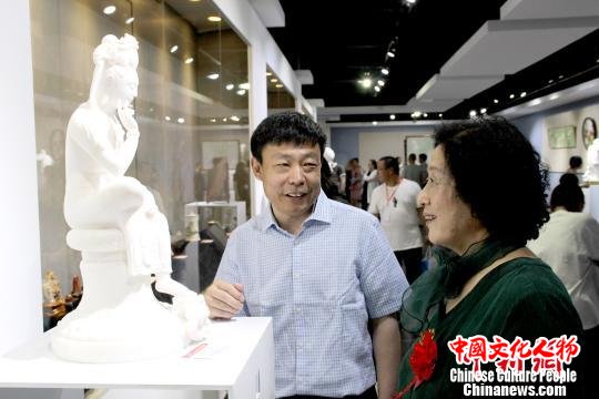 中国工艺美术大师刘红立(左)向观众介绍其汉白玉作品《思维菩萨》的创作初衷。　赵庆斌 摄