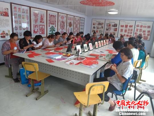 图为村民在非遗扶贫就业工坊练习剪纸 冯维健 摄