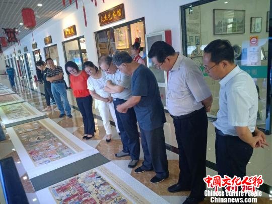 图为张冬阁(右三)向到场嘉宾介绍自己的画作 冯维健 摄